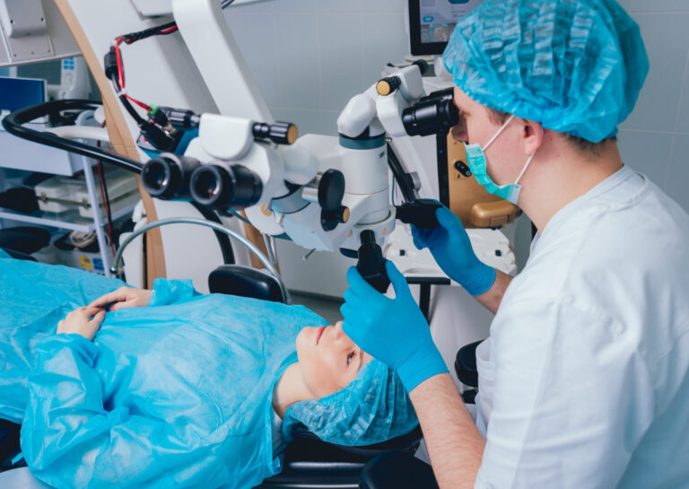 Paciente acostada bajo el microscopio quirúrgico durante una cirugía ocular