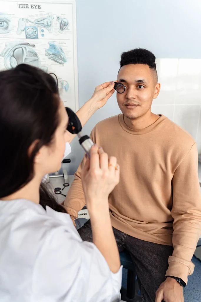 Especialista revisa el ojo de un paciente con un oftalmoscopio